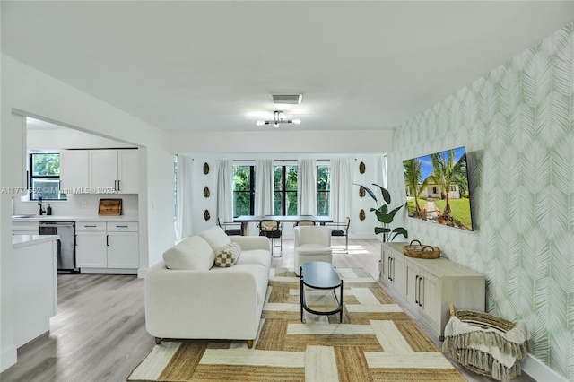 2515 NE 207th St, Miami, FL 33180 - living room featuring an accent wall, visible vents, baseboards, wallpapered walls, and light wood-style floors
