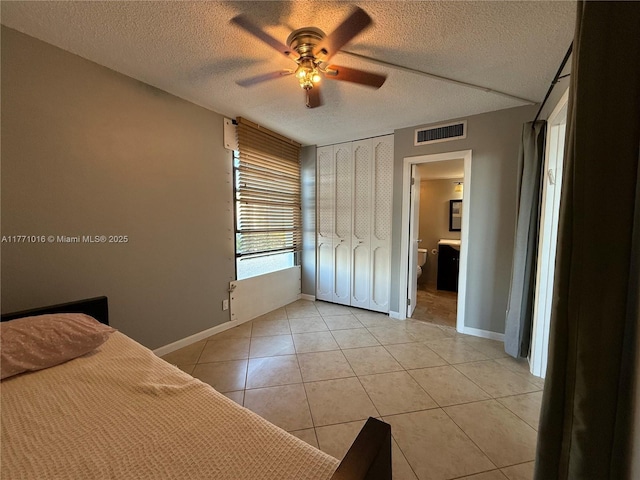 bedroom with light tile patterned flooring, a textured ceiling, visible vents, and baseboards