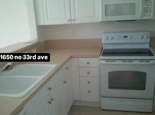 1650 NE 33rd Ave Unit 105-7, Homestead, FL 33033 - kitchen featuring white cabinets, a sink, light tile patterned flooring, and white appliances