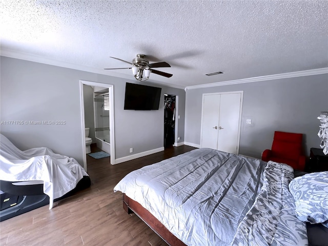 bedroom with crown molding, wood finished floors, a textured ceiling, a closet, and visible vents