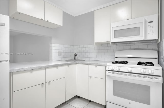 kitchen featuring white cabinets, a sink, decorative backsplash, white appliances, and light stone counters