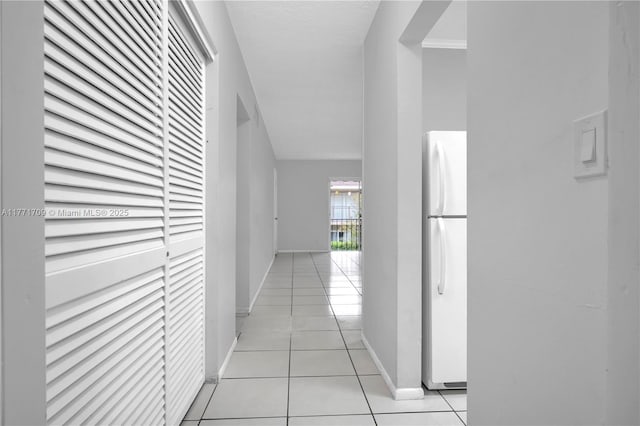 corridor with baseboards and light tile patterned flooring