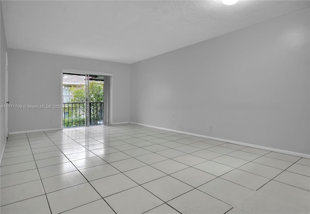 empty room featuring light tile patterned flooring, a textured ceiling, and baseboards