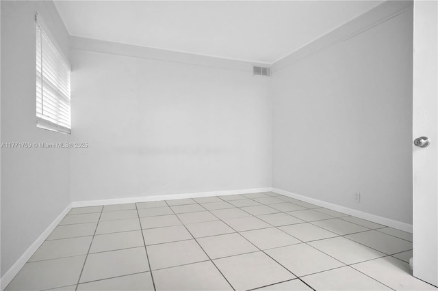 empty room featuring baseboards, visible vents, and light tile patterned flooring
