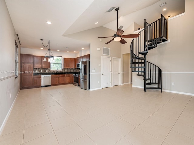 unfurnished living room with visible vents, light tile patterned floors, a sink, ceiling fan, and stairs