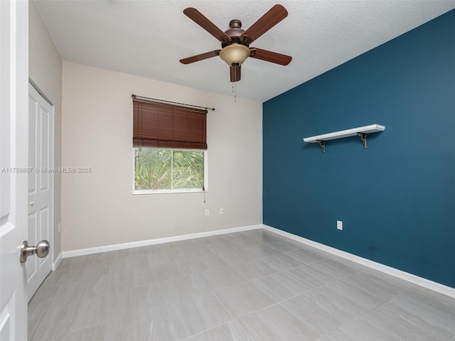 unfurnished room with light tile patterned flooring, a textured ceiling, baseboards, and ceiling fan