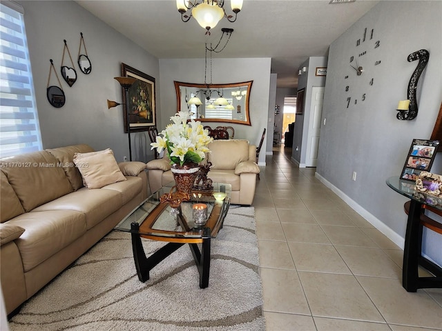 living area with light tile patterned flooring, a notable chandelier, baseboards, and a healthy amount of sunlight