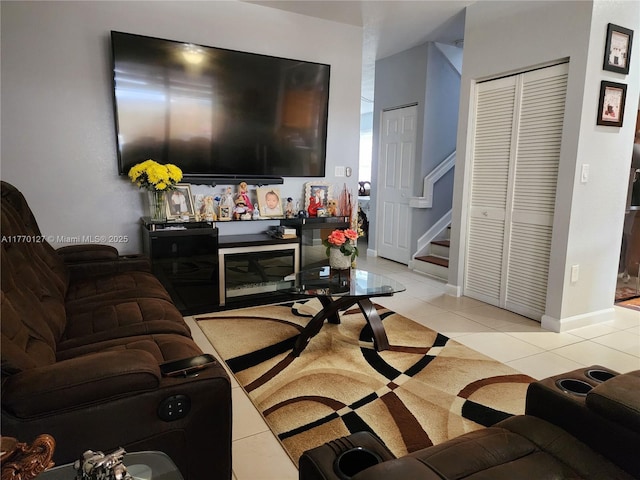 living room featuring light tile patterned flooring, baseboards, and stairway