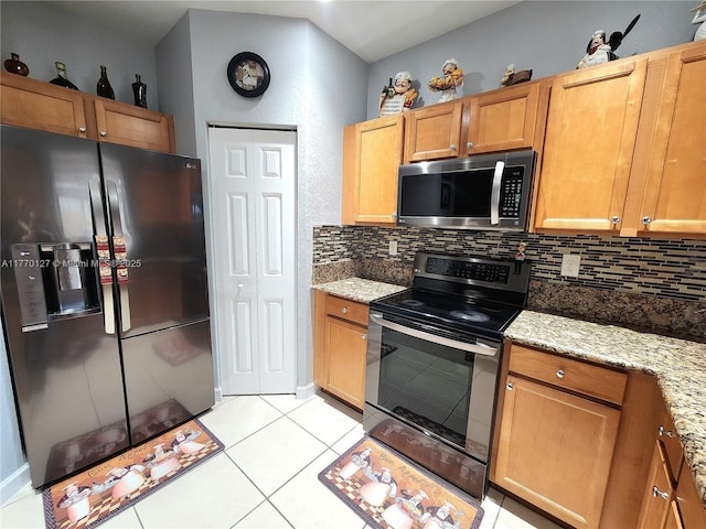 kitchen featuring light tile patterned floors, light stone countertops, tasteful backsplash, and appliances with stainless steel finishes