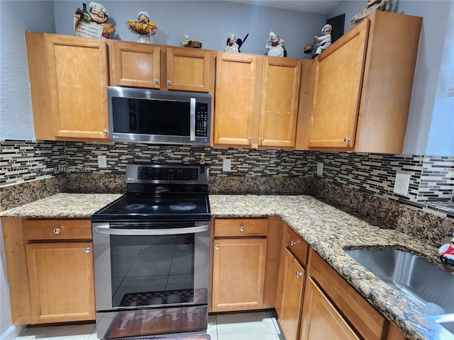 kitchen featuring a sink, stainless steel appliances, light stone countertops, and decorative backsplash