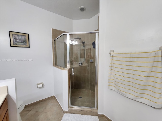 bathroom featuring a stall shower, toilet, vanity, tile patterned flooring, and baseboards