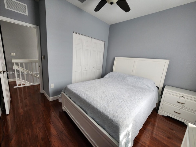 bedroom with dark wood-style flooring, baseboards, visible vents, a ceiling fan, and a closet