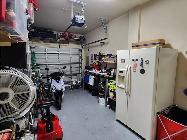 garage with a garage door opener and white refrigerator with ice dispenser