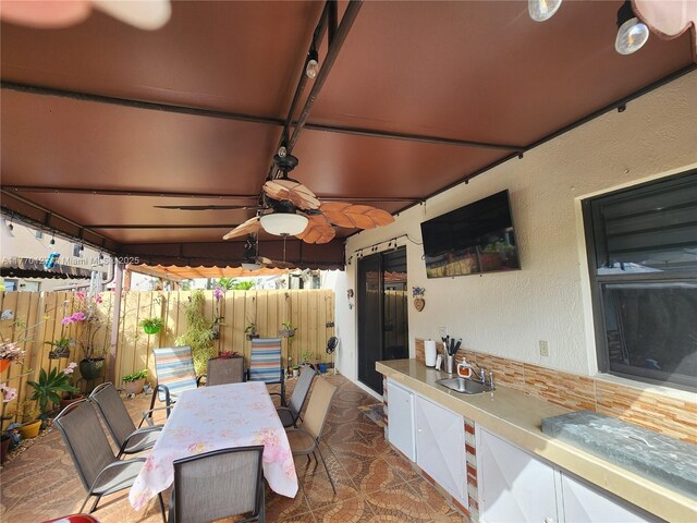 view of patio / terrace with outdoor dining area, a sink, fence, and a ceiling fan