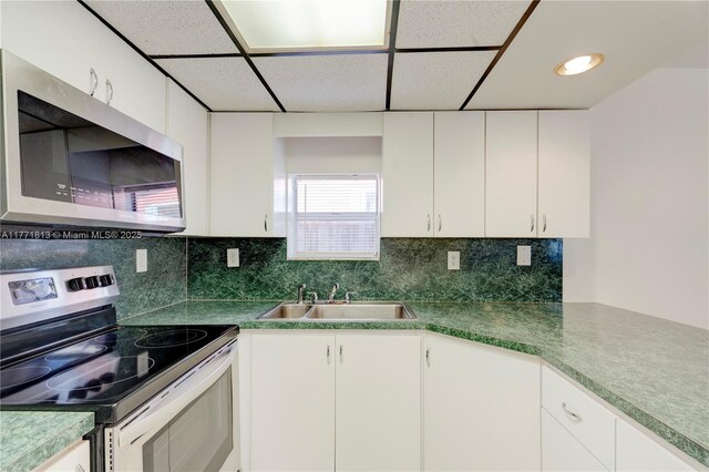6288 SW 22nd Ct, Miramar, FL 33023 - kitchen featuring tasteful backsplash, appliances with stainless steel finishes, white cabinetry, a sink, and a drop ceiling