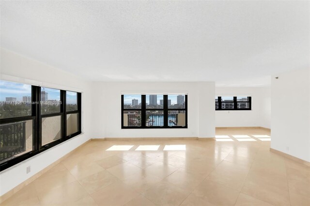 empty room with baseboards, a wealth of natural light, and a city view