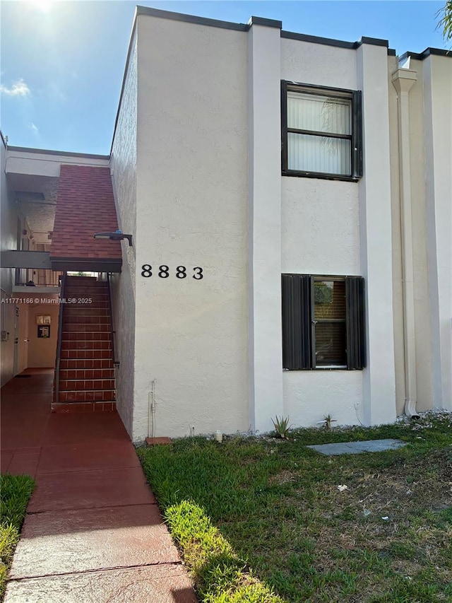 view of property exterior featuring stucco siding and stairs