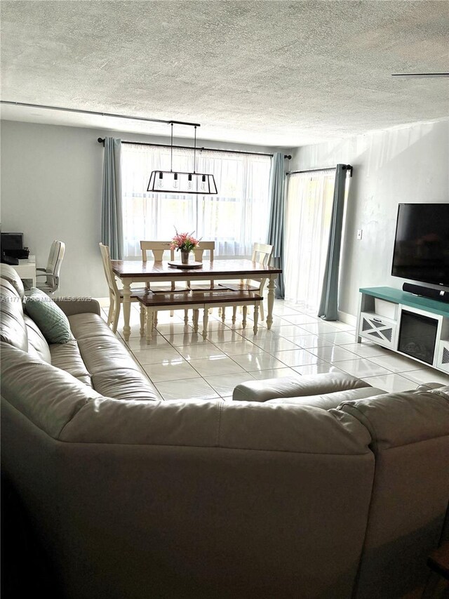 living room featuring light tile patterned flooring, a textured ceiling, and baseboards