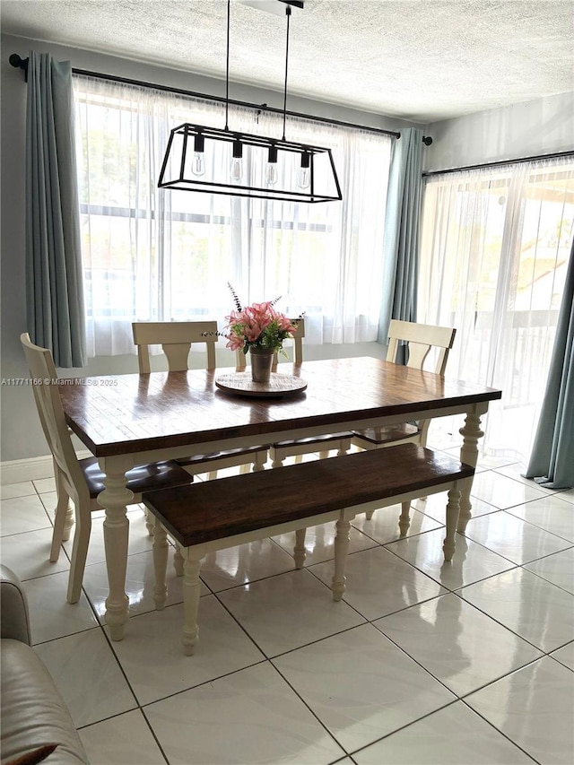 dining area with a textured ceiling and light tile patterned flooring