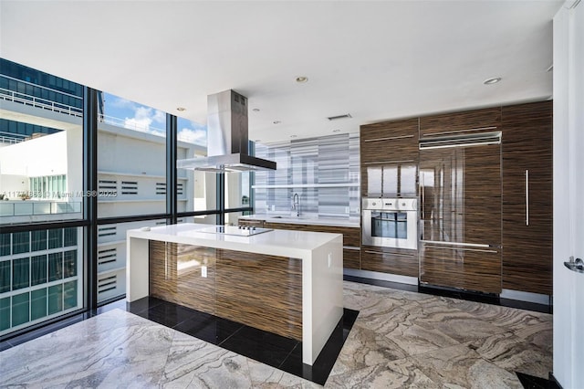 1100 Biscayne Blvd Unit 4901, Miami, FL 33132 - kitchen featuring island exhaust hood, oven, modern cabinets, marble tiled flooring, and built in fridge