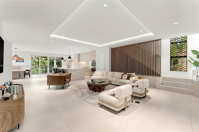 living room featuring a tray ceiling, light tile patterned flooring, and recessed lighting