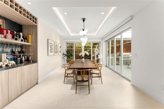 dining area with a raised ceiling, light tile patterned floors, baseboards, and recessed lighting