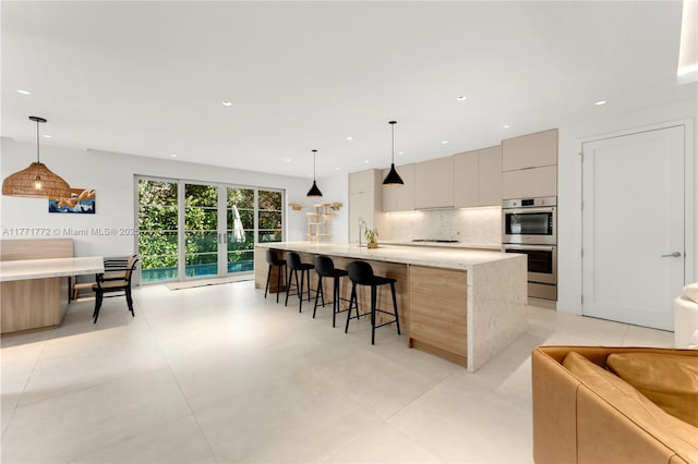kitchen featuring stainless steel double oven, tasteful backsplash, a breakfast bar area, modern cabinets, and stovetop