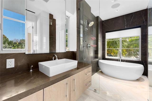 full bath with a freestanding bath, plenty of natural light, tiled shower, and vanity