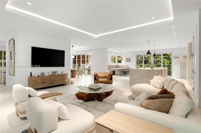 living area with a tray ceiling, a chandelier, and recessed lighting
