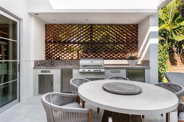 view of patio with a grill, outdoor dining space, exterior kitchen, and a sink