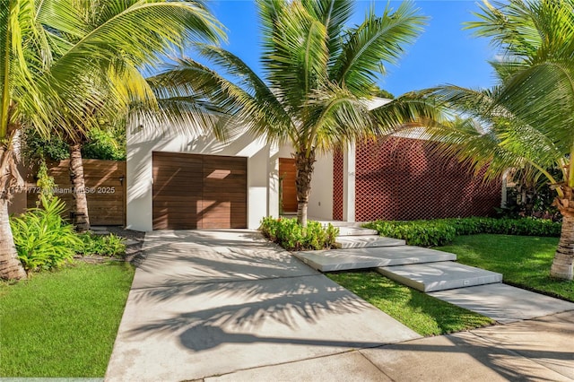 view of front facade featuring a garage, driveway, stucco siding, and a front lawn