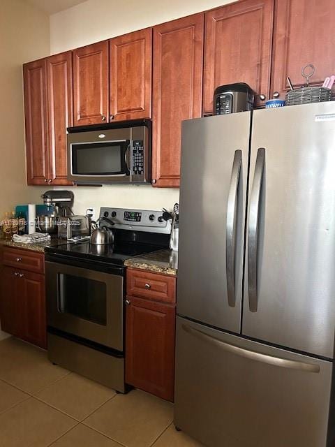 3001 NE 185th St Unit 418, Aventura, FL 33180 - kitchen featuring stainless steel appliances, light tile patterned floors, and dark stone countertops