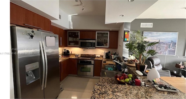 kitchen with visible vents, track lighting, appliances with stainless steel finishes, glass insert cabinets, and a sink