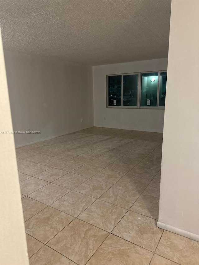 unfurnished room with light tile patterned flooring and a textured ceiling
