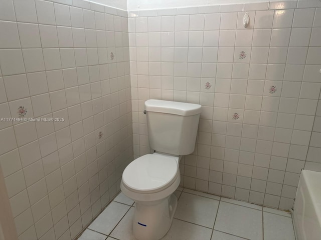 bathroom with tile walls, a bath, tile patterned flooring, and toilet
