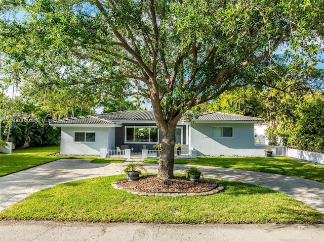 1259 NE 98th St, Miami Shores, FL 33138 - single story home featuring a front yard, a tiled roof, covered porch, stucco siding, and curved driveway