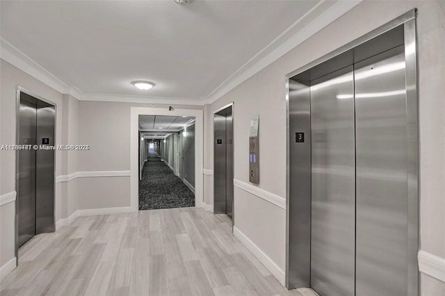 corridor with baseboards, elevator, ornamental molding, and light wood-type flooring