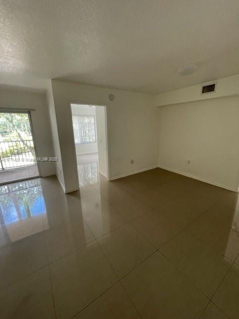 4271 San Marino Blvd Unit 206, West Palm Beach, FL 33409 - spare room with baseboards, visible vents, dark tile patterned flooring, and a textured ceiling