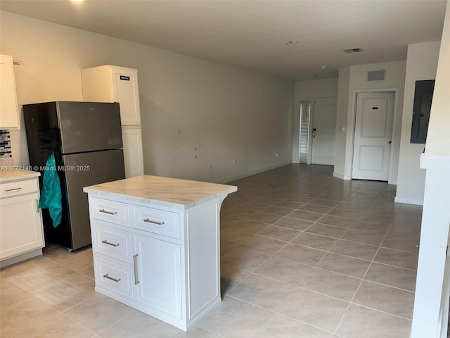 kitchen with white cabinets, visible vents, electric panel, and freestanding refrigerator
