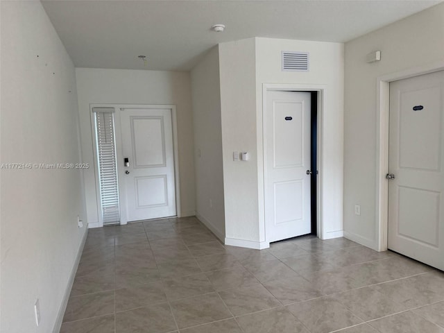 unfurnished room featuring light tile patterned flooring, baseboards, and visible vents