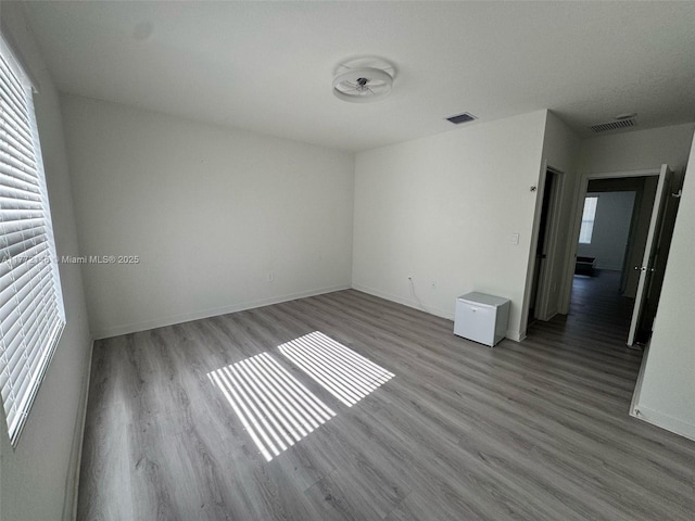 spare room with baseboards, visible vents, and wood finished floors