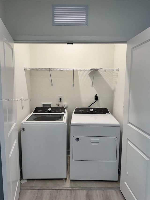 clothes washing area featuring washing machine and dryer, visible vents, and laundry area