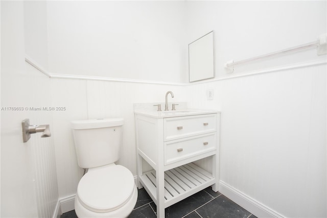 bathroom with vanity, toilet, tile patterned floors, and wainscoting