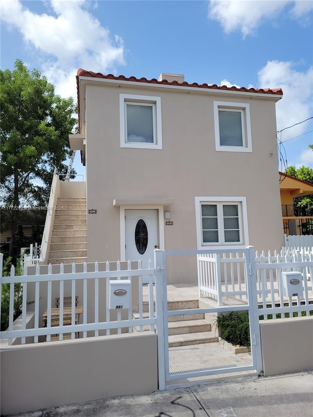 view of front of property featuring stucco siding, a fenced front yard, and stairway