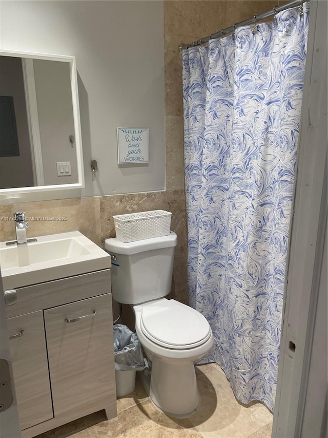 bathroom featuring tile walls, toilet, curtained shower, vanity, and wainscoting