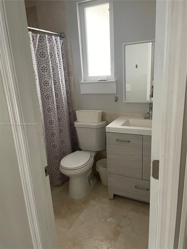 full bath featuring toilet, a shower with shower curtain, and vanity