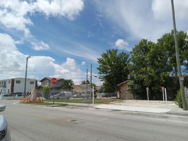 view of street with sidewalks, curbs, traffic signs, and a residential view
