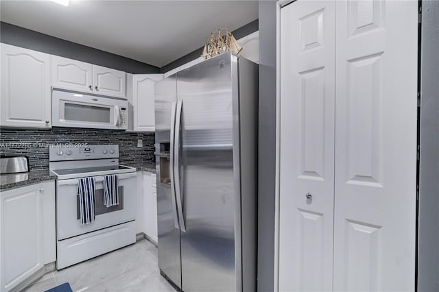 kitchen with white appliances, dark stone counters, white cabinets, and tasteful backsplash