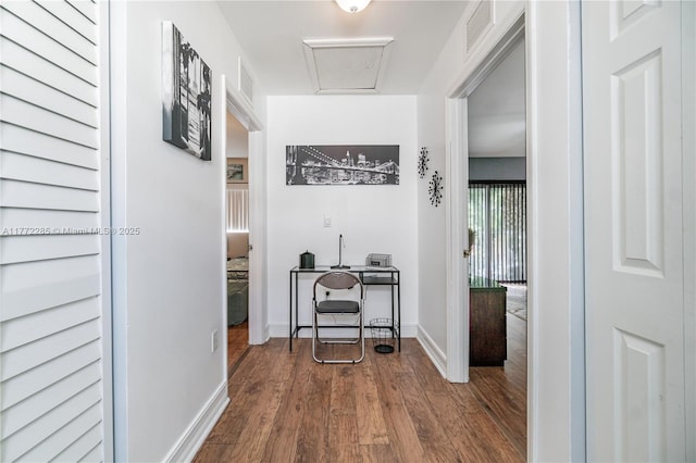 hallway featuring dark wood-style floors, visible vents, and baseboards