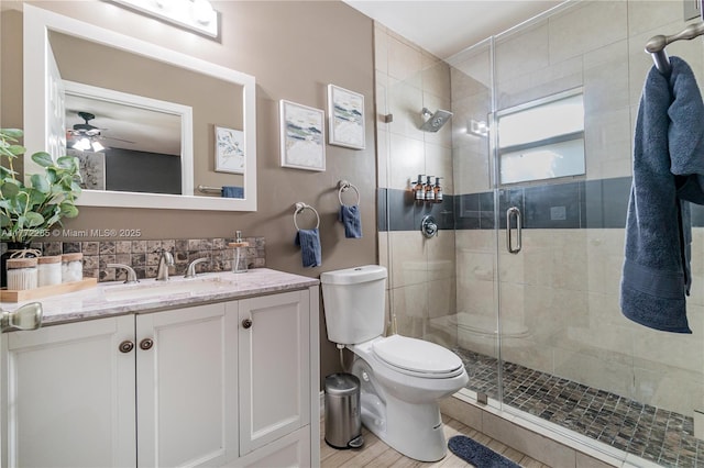 full bathroom with a ceiling fan, toilet, vanity, and a shower stall